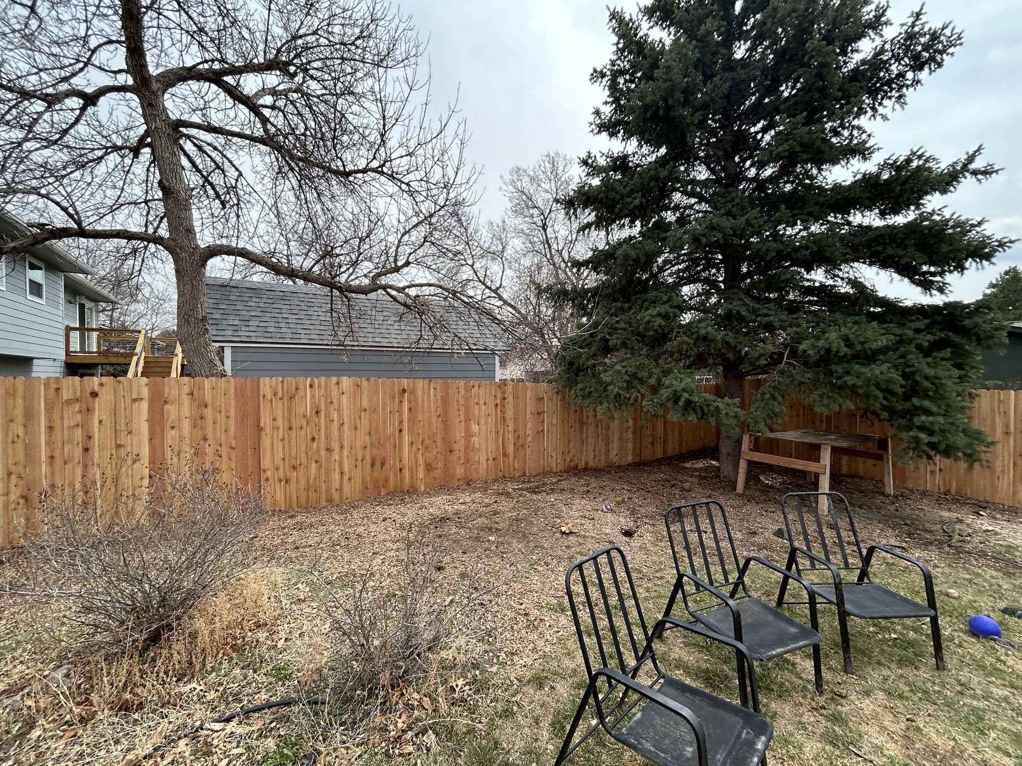 Finished wood fence enclosing a backyard patio seating area