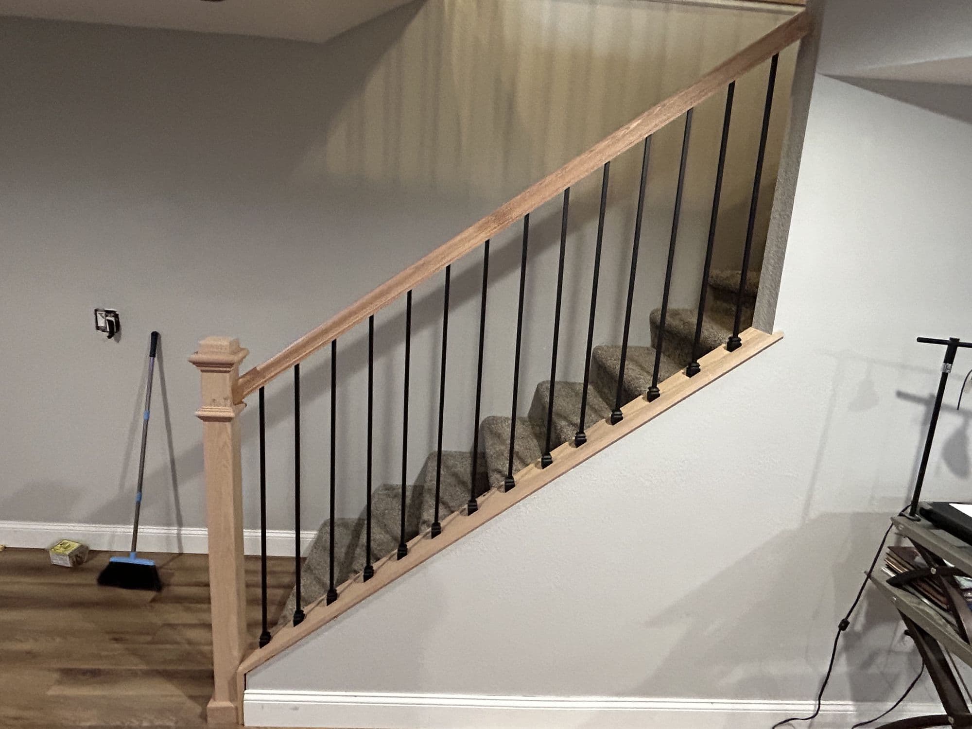 Finished stair railing with black balusters and wood cap